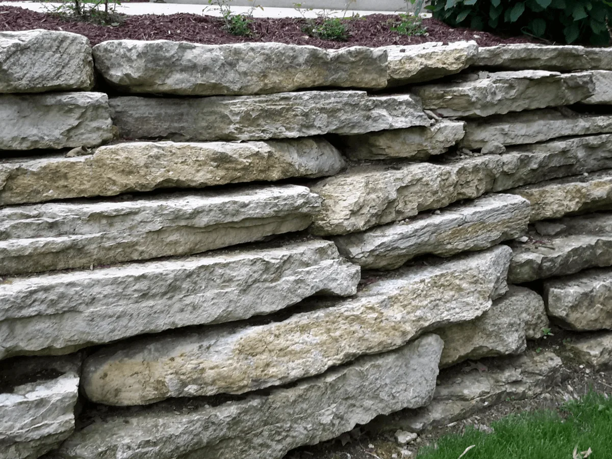 Dry stacked limestone retaining wall holding a raised bed above a lawn, retaining walls